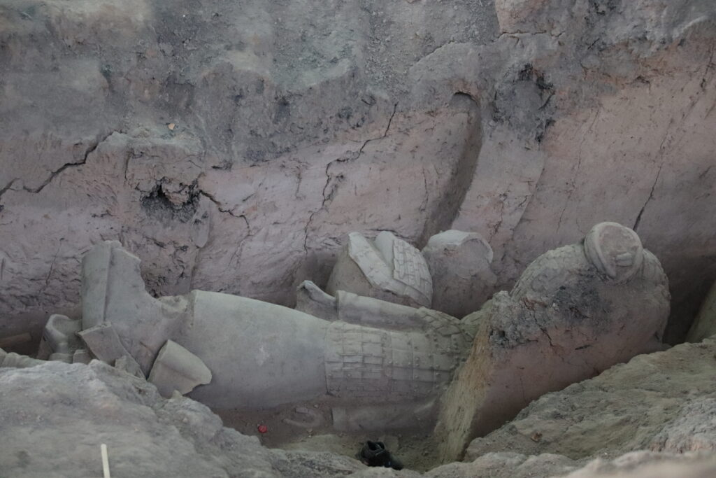 Partly excavated terracotta figures in an earthen trench