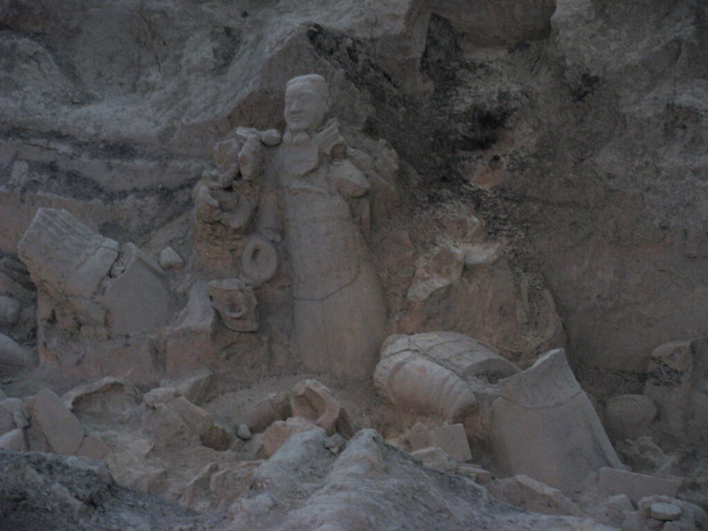 Unrestored terracotta warrior surrounded by fragments