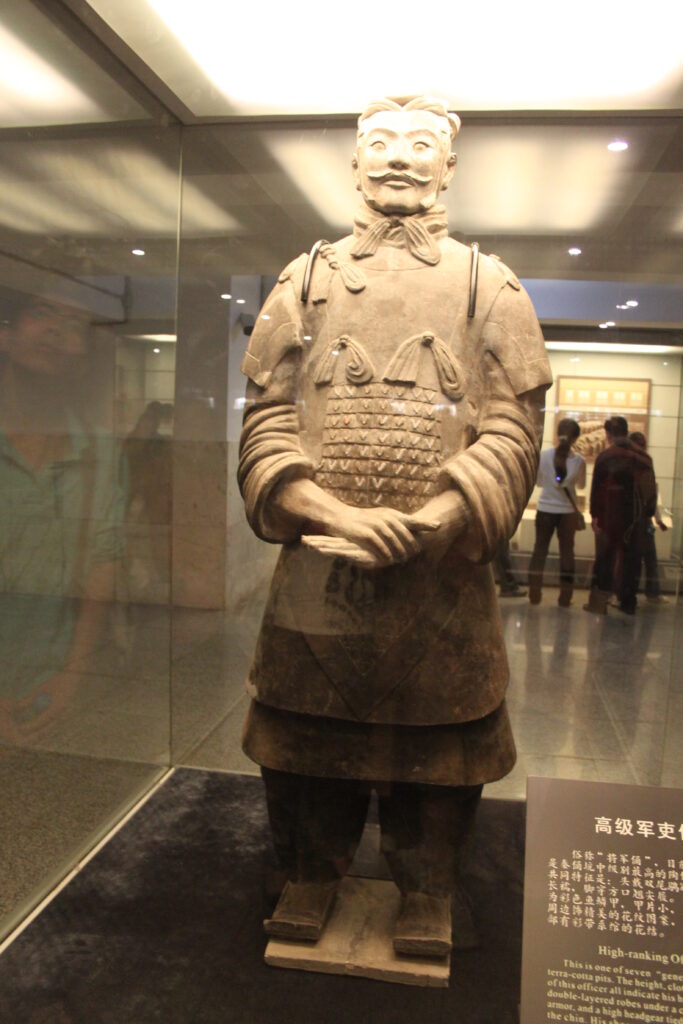 High-ranking Terracotta Army officer with elaborate headgear, armor, and hands crossed at the waist